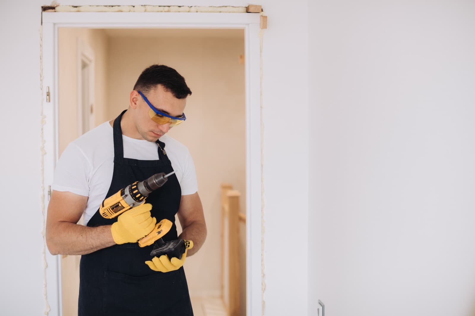 Repair worker with a drill beside a door frame