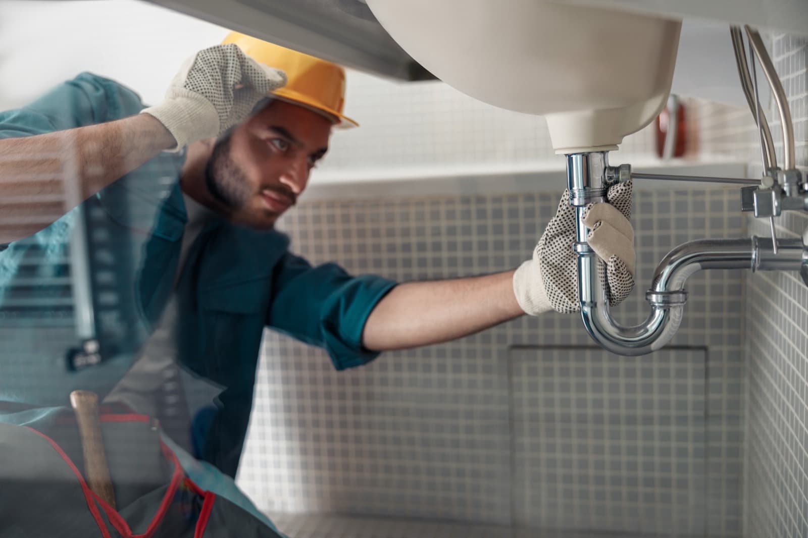 Plumber repairing a bathroom sink faucet in a Carrollton home