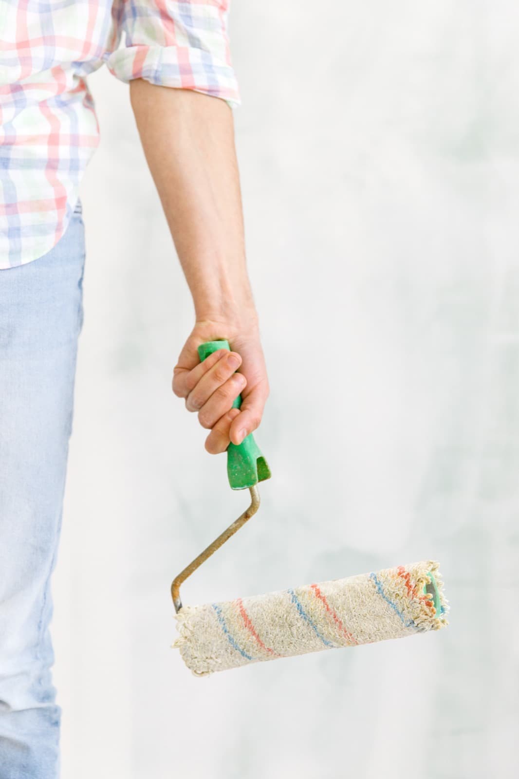 Painter holding a roller beside an interior wall