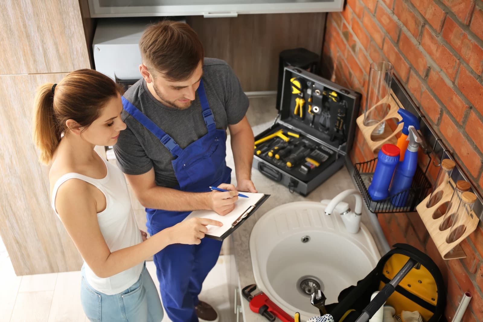 Plumber consulting with a homeowner near a kitchen sink in a newer Aledo home
